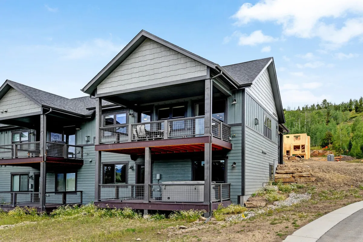 The image features the exterior of the chalet, showcasing inviting balconies, well-maintained exterior siding, and lush landscaping. The outdoor spaces appear perfect for gathering, offering beautiful views for relaxing or spending time with family and friends.