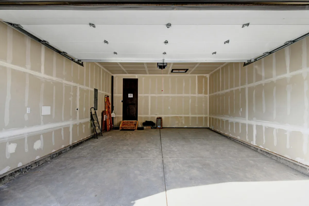 A practical garage space with visible garage door, entrance, storage tools, and workbench—suggesting secure parking and ample storage for outdoor gear like skis and bikes.