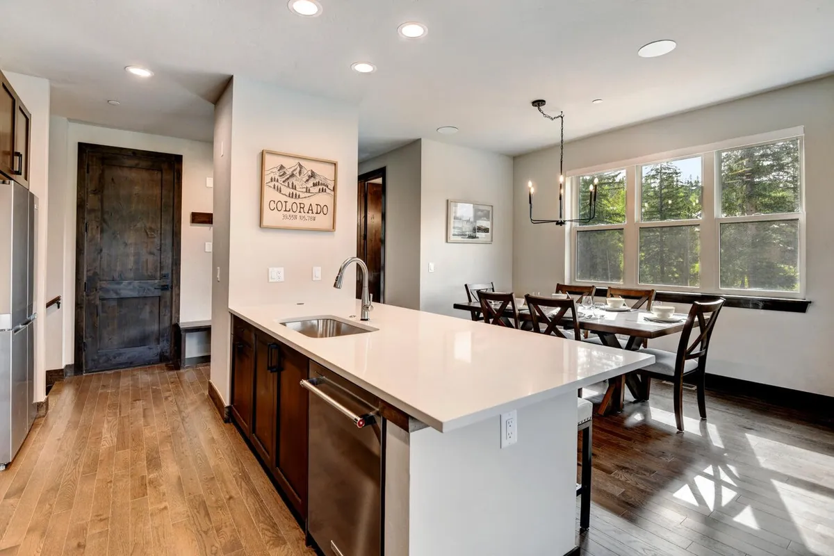 A bright and airy kitchen and dining area featuring a kitchen island with stainless steel appliances, plenty of natural light, and artwork on the walls. The adjoining dining area encourages shared meals and intimate gatherings.
